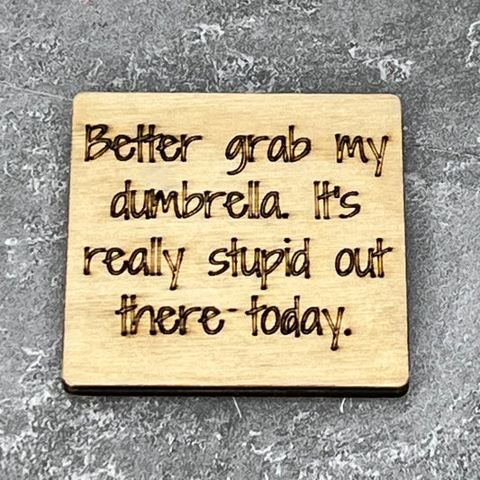 2" wood square with “Better grab my dumbrella.  It’s really stupid out there today.“ laser engraved