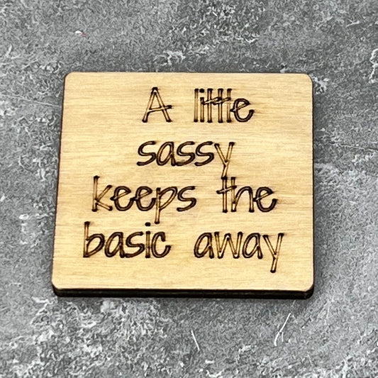 2" wood square with “A little sassy keeps the basic away“ laser engraved