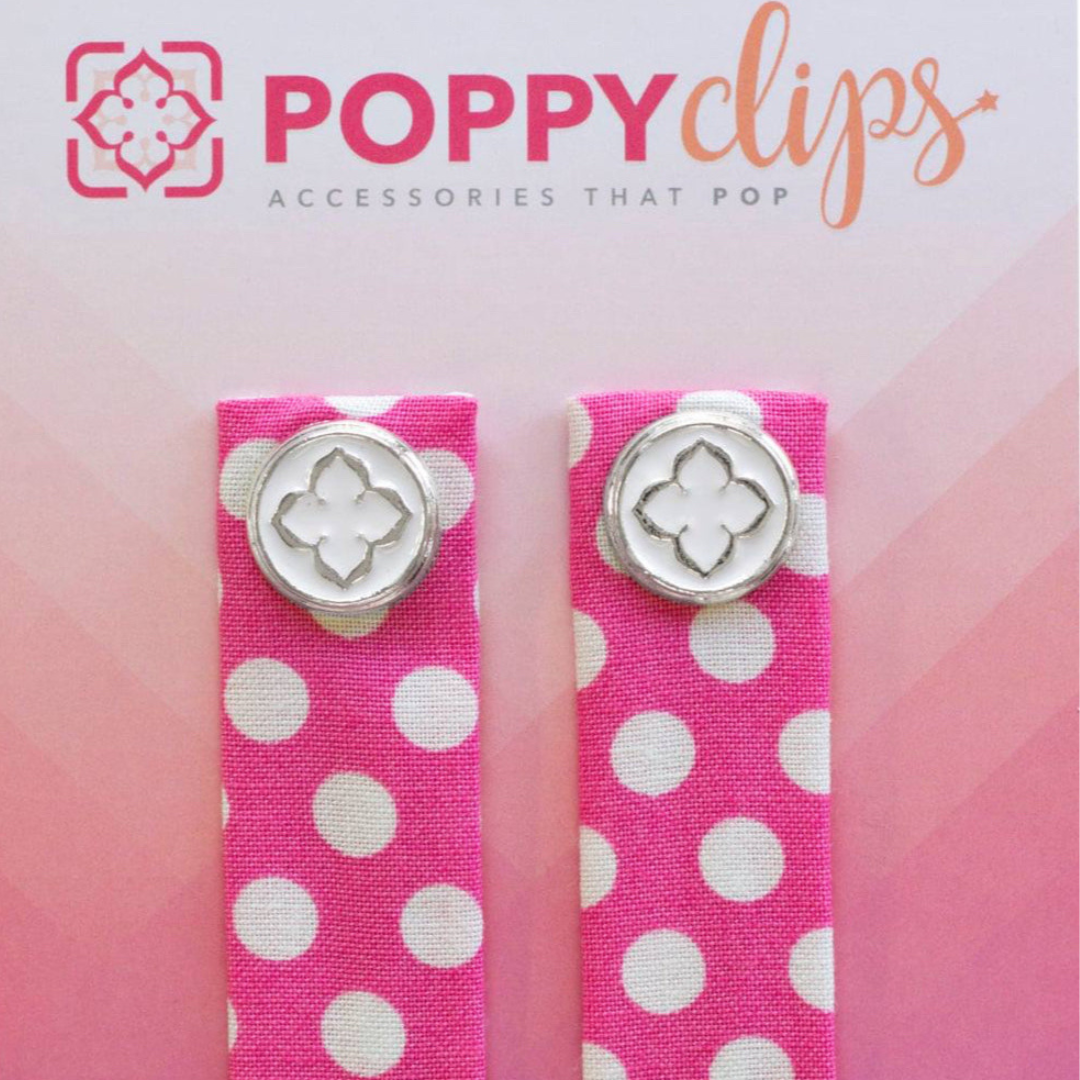 Two 5 ¼” long by 7/8” wide bright pink material with white polka dots, and a magnet at each end. The outer magnet is a decorative silver medallion with the company logo.