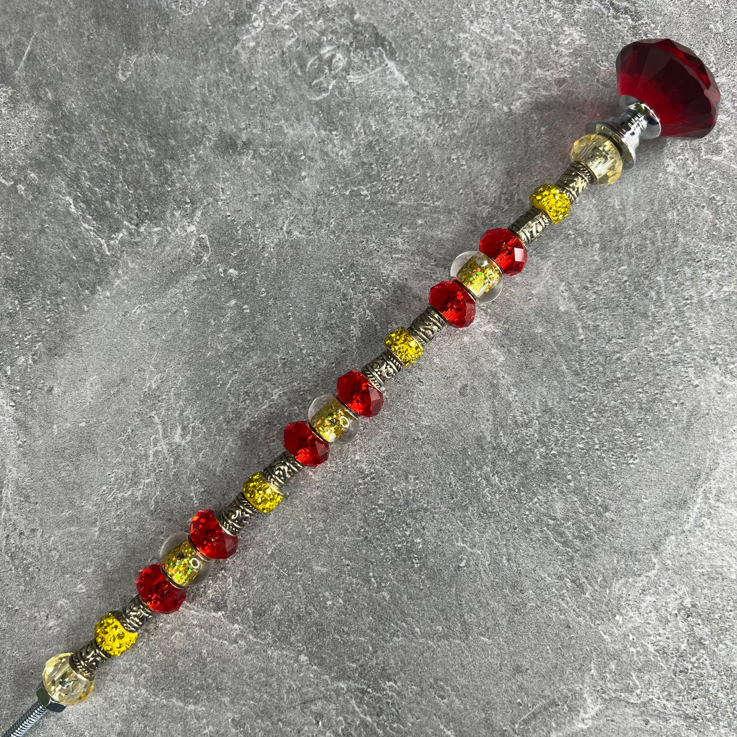 A crimson metal garden stake with a sun design — elegant outdoor decor for a sunny garden.