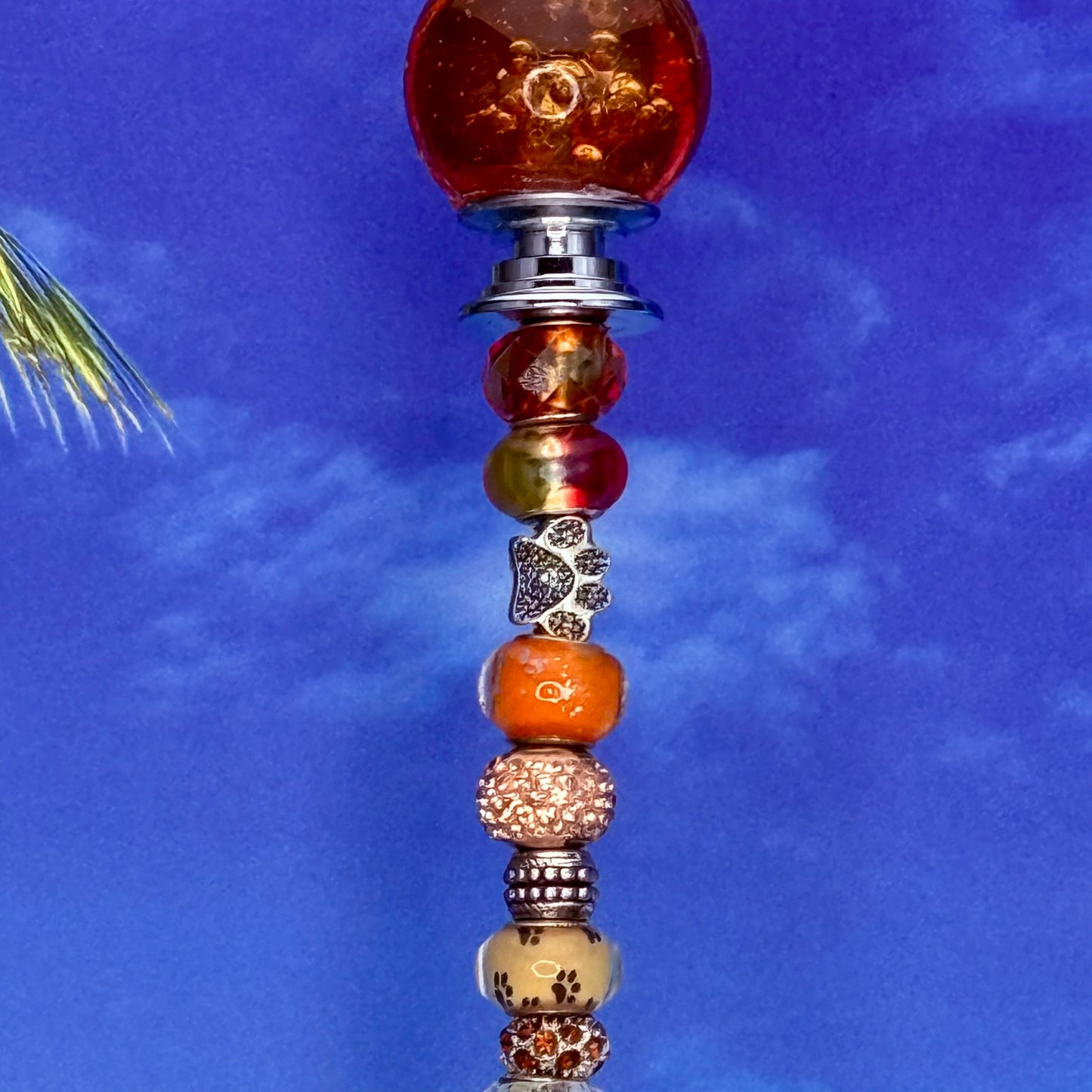 Orange garden stake with paw print and ‘Paws in Paradise’ — cheerful outdoor pet-themed décor.