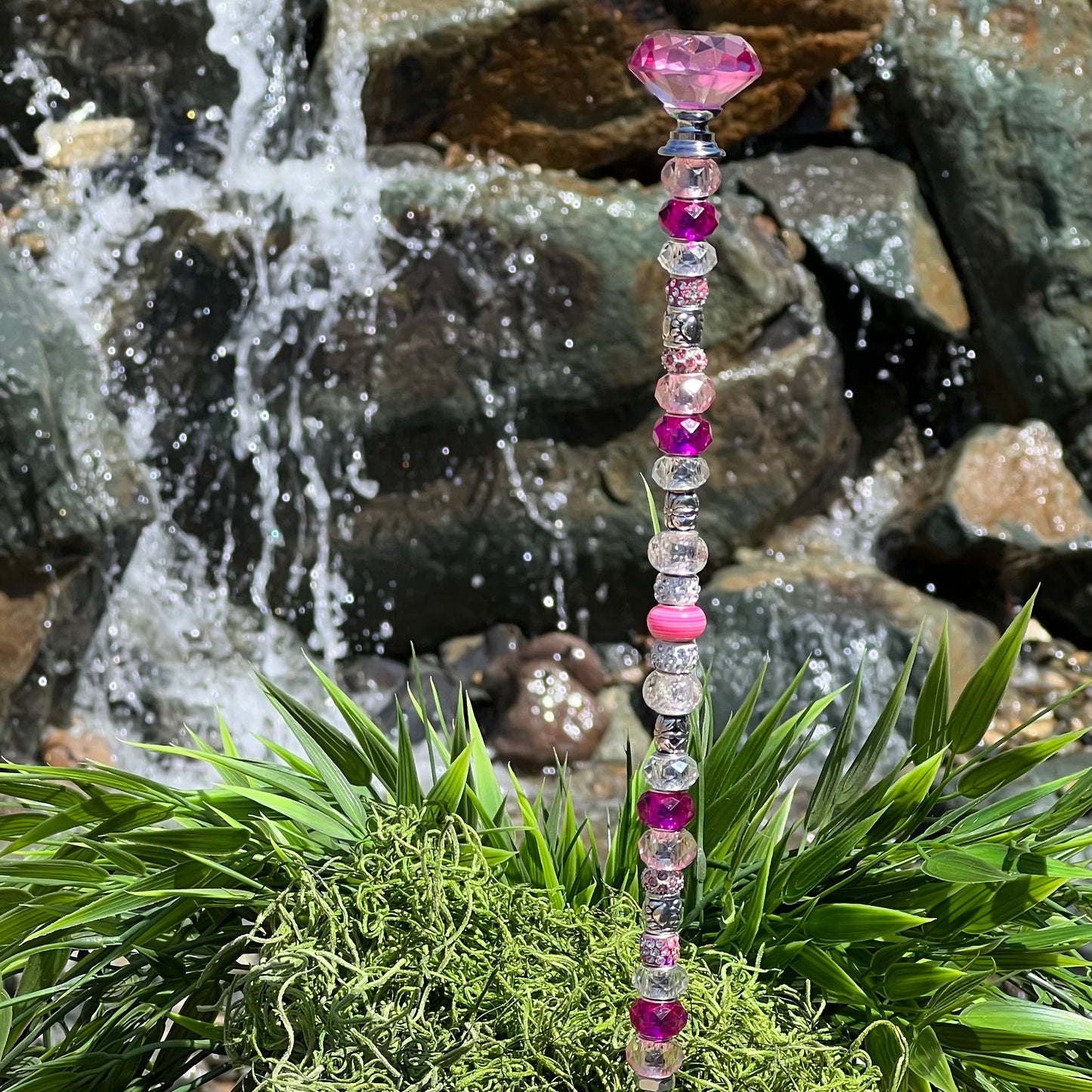 Pink metal garden stake with paw print and jeweled topper — cute outdoor decor for pet lovers.