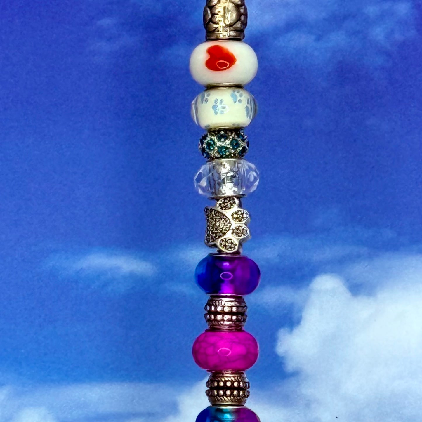 Colorful garden stake with rainbow paw prints and hearts — playful outdoor décor for pet lovers.