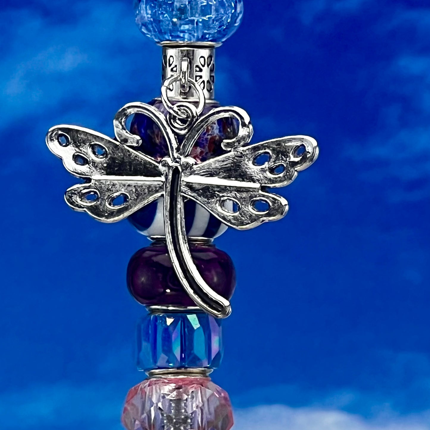 Metal garden stake featuring a dragonfly and tri‑tone blossom breeze in pink, blue, and purple — whimsical outdoor décor.