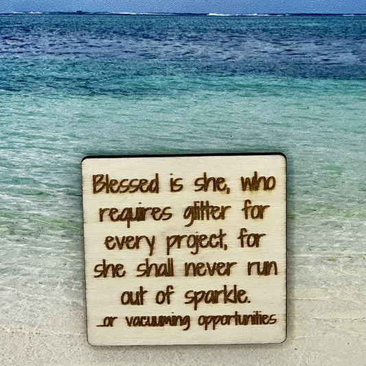 2”x2” wooden square with “Blessed is She, Who Requires Glitter For Every Project, For She Shall Never Run Our of Sparkle. ...or Vacuuming Opportunities“ laser engraved. Background scene is a tropical ocean.