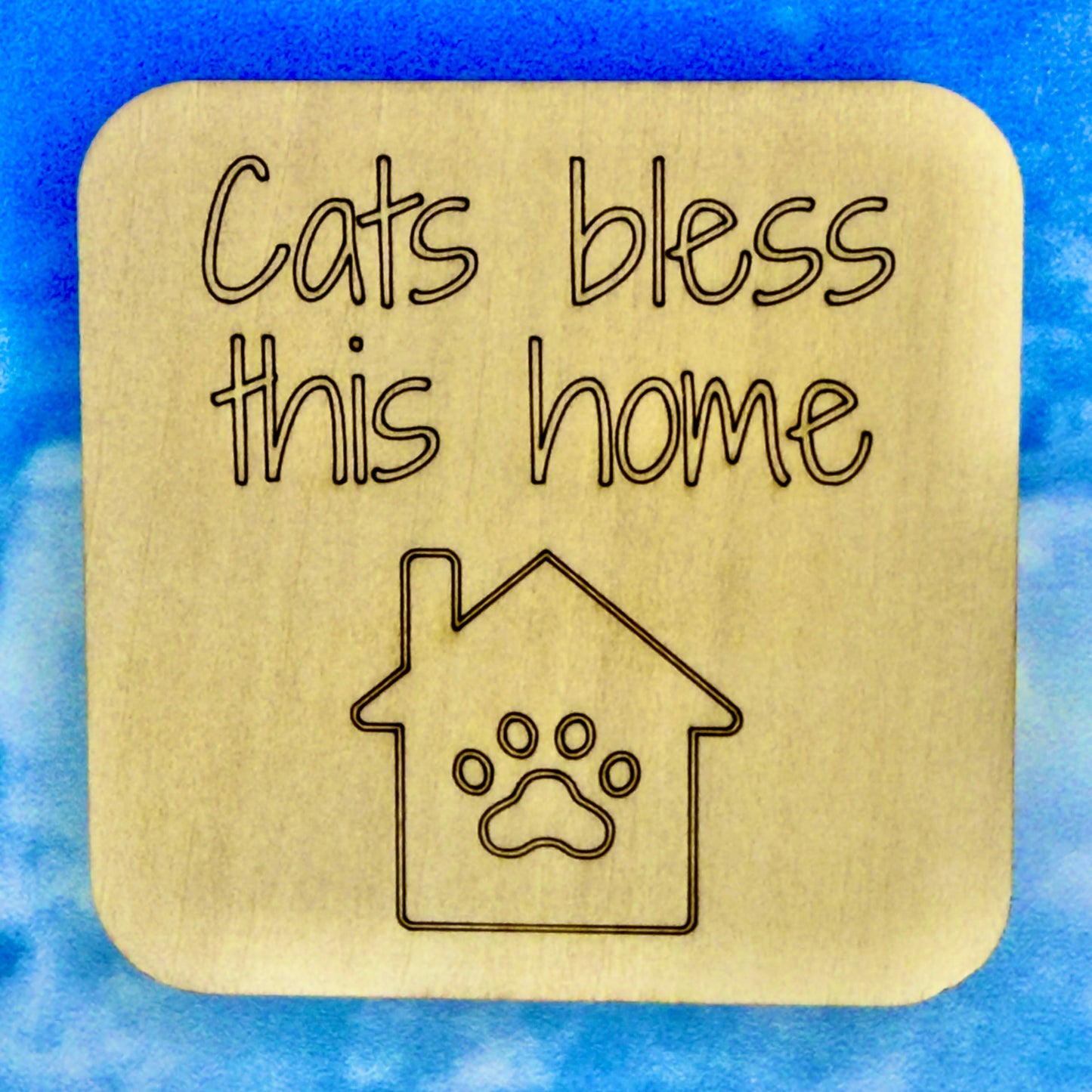 2.5" basewood square with “Cats bless this home“ laser engraved text with image of a house and a paw.