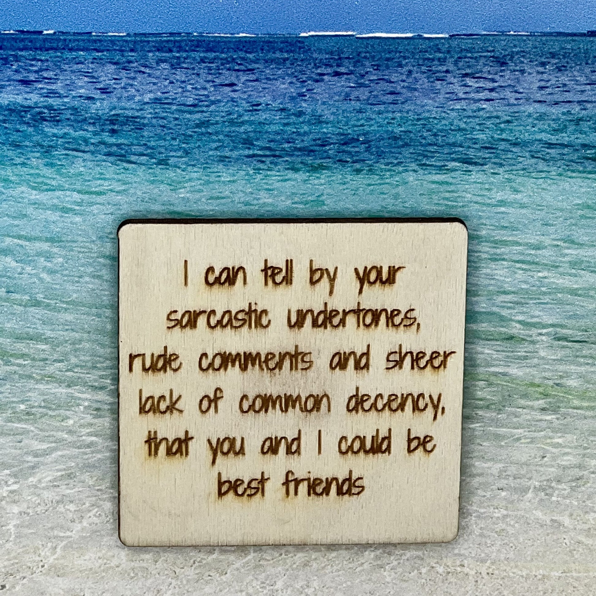 2”x2” wooden square with “ I Can Tell by Your Sarcastic Undertones, Rude Comments and Sheer Lack of Common Decency, That You and I Could Be Best Friends“ laser engraved. Background scene is a tropical ocean.