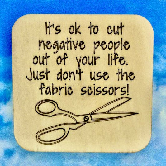 2.5" basewood square with “It's ok to cut negative people out of your life… just don't use the fabric scissors“ laser engraved text with image of fabric scissors.