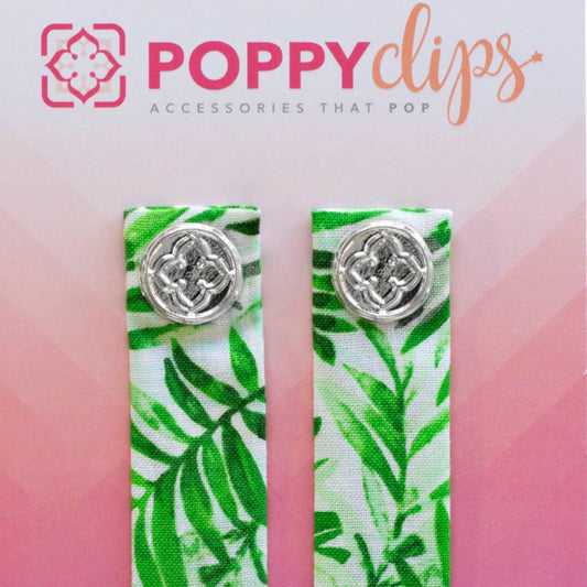 Two 5 ¼” long by 7/8” wide white with green palm fronds material, with a magnet at each end.  The outer magnet is a decorative silver medallion with the company logo.