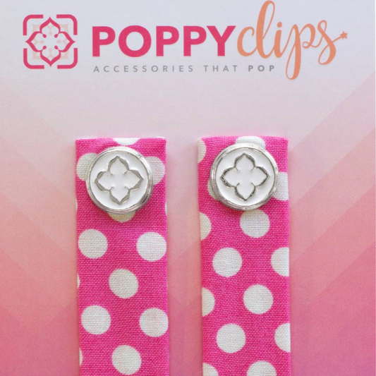 Two 5 ¼” long by 7/8” wide bright pink material with white polka dots, and a magnet at each end.  The outer magnet is a decorative silver medallion with the company logo. 