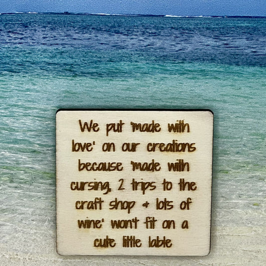 2”x2” wooden square with “We Put "Made with Love" because "Made with Cursing, 2 Trips to the Craft Shop + Lot's of Wine" Doesn't Fit on a Little Lable“ laser engraved. Background scene is a tropical ocean.