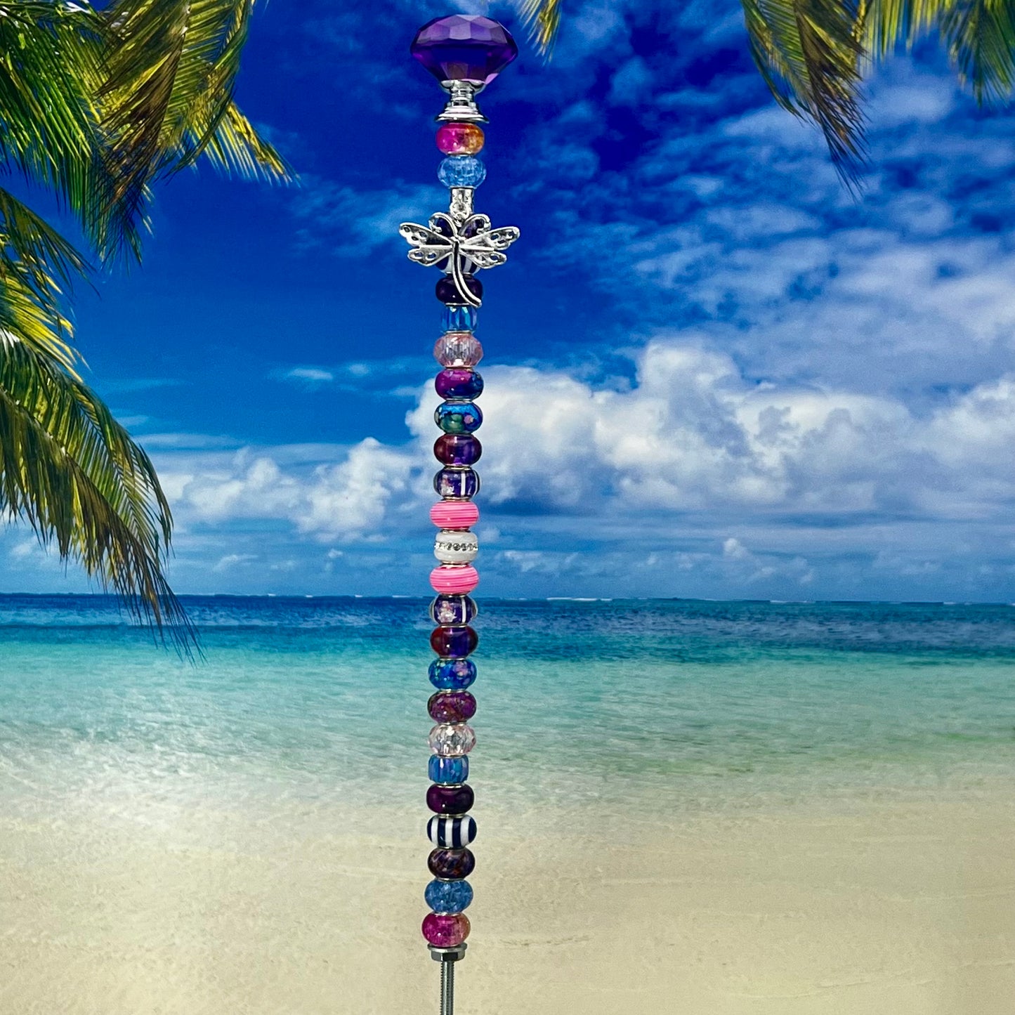 Metal garden stake with dragonfly and blossom design in pink, blue, and purple — whimsical and colorful outdoor décor.
