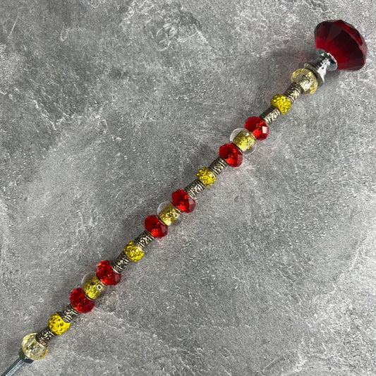 A crimson metal garden stake with a sun design — elegant outdoor decor for a sunny garden.
