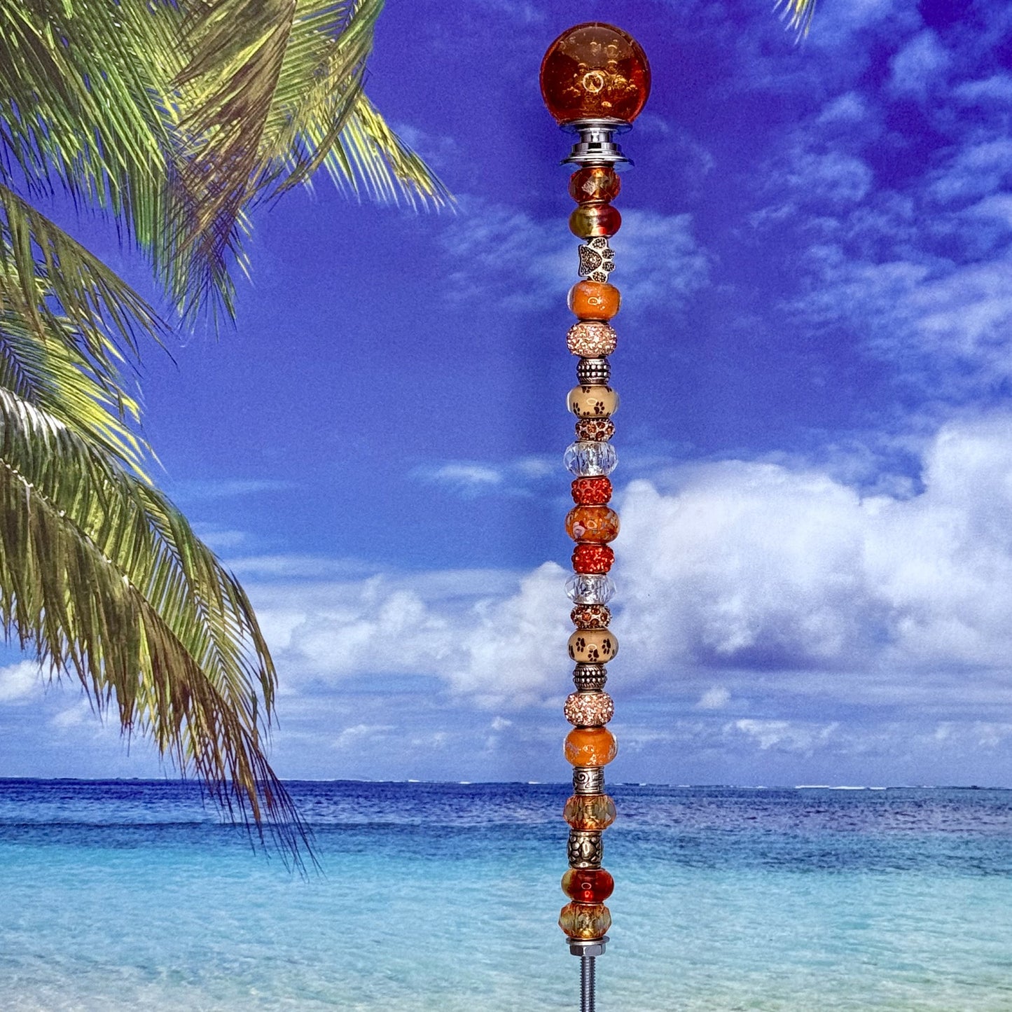 Orange garden stake with paw print and ‘Paws in Paradise’ — cheerful outdoor pet-themed décor.
