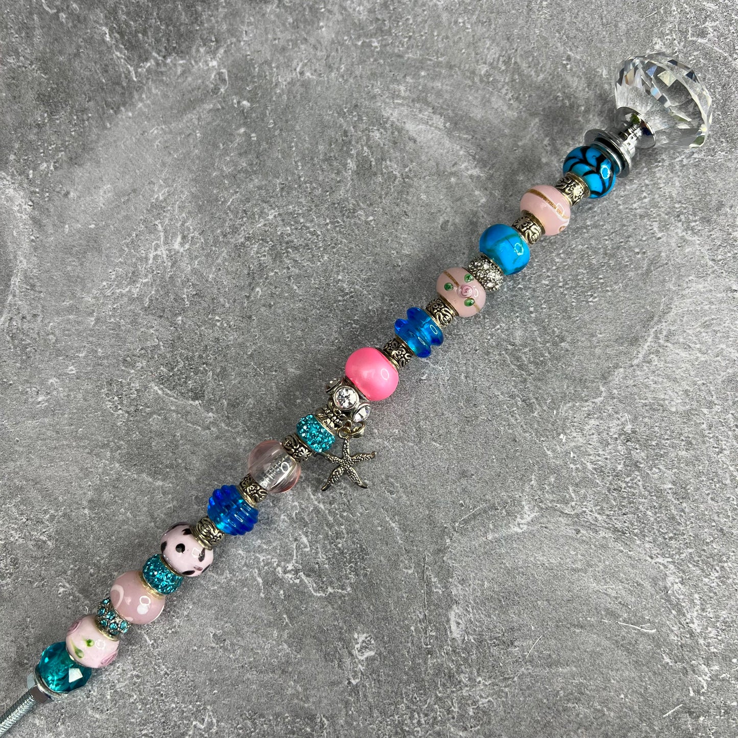 Pink starfish garden stake with blue metal base — coastal outdoor décor.
