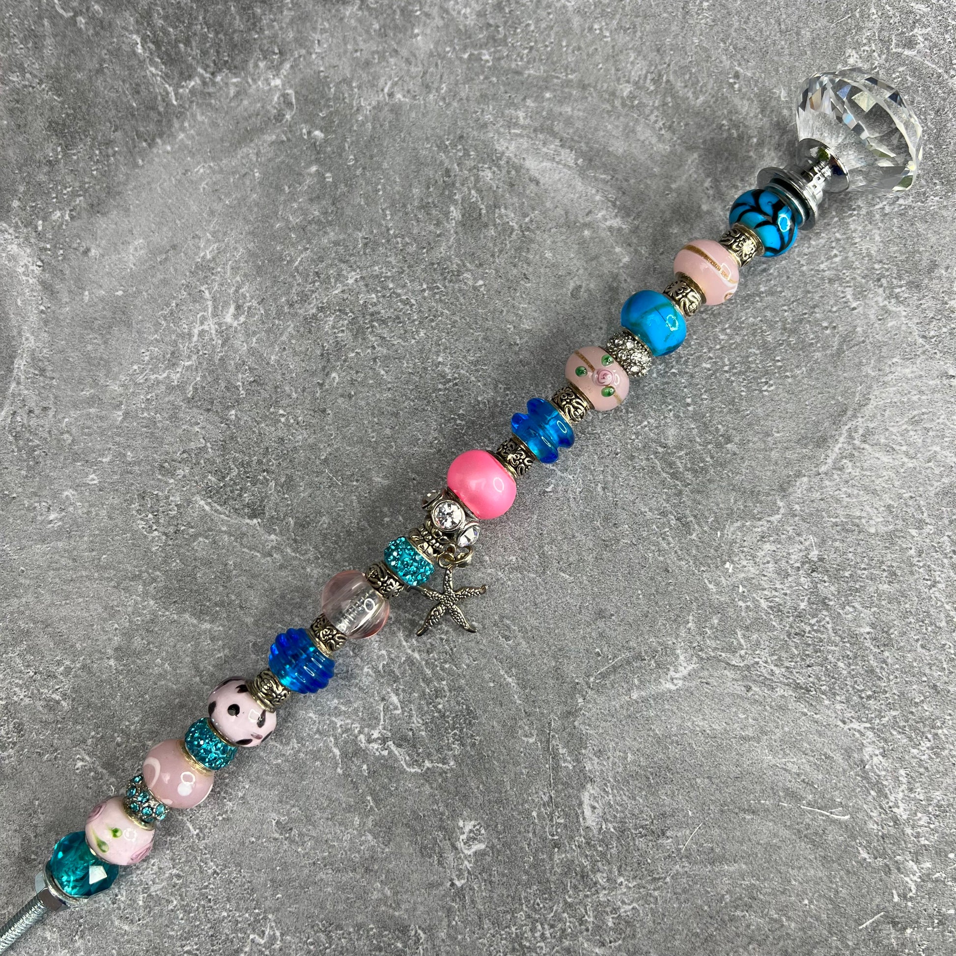 Pink starfish garden stake with blue metal base — coastal outdoor décor.
