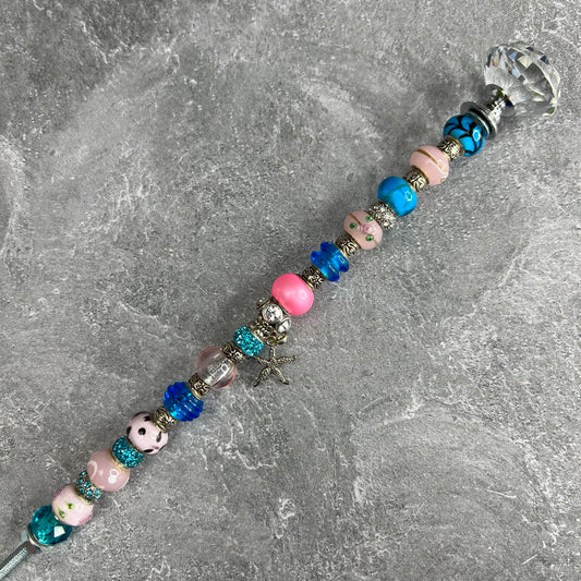 Pink starfish garden stake with blue metal base — coastal outdoor décor.
