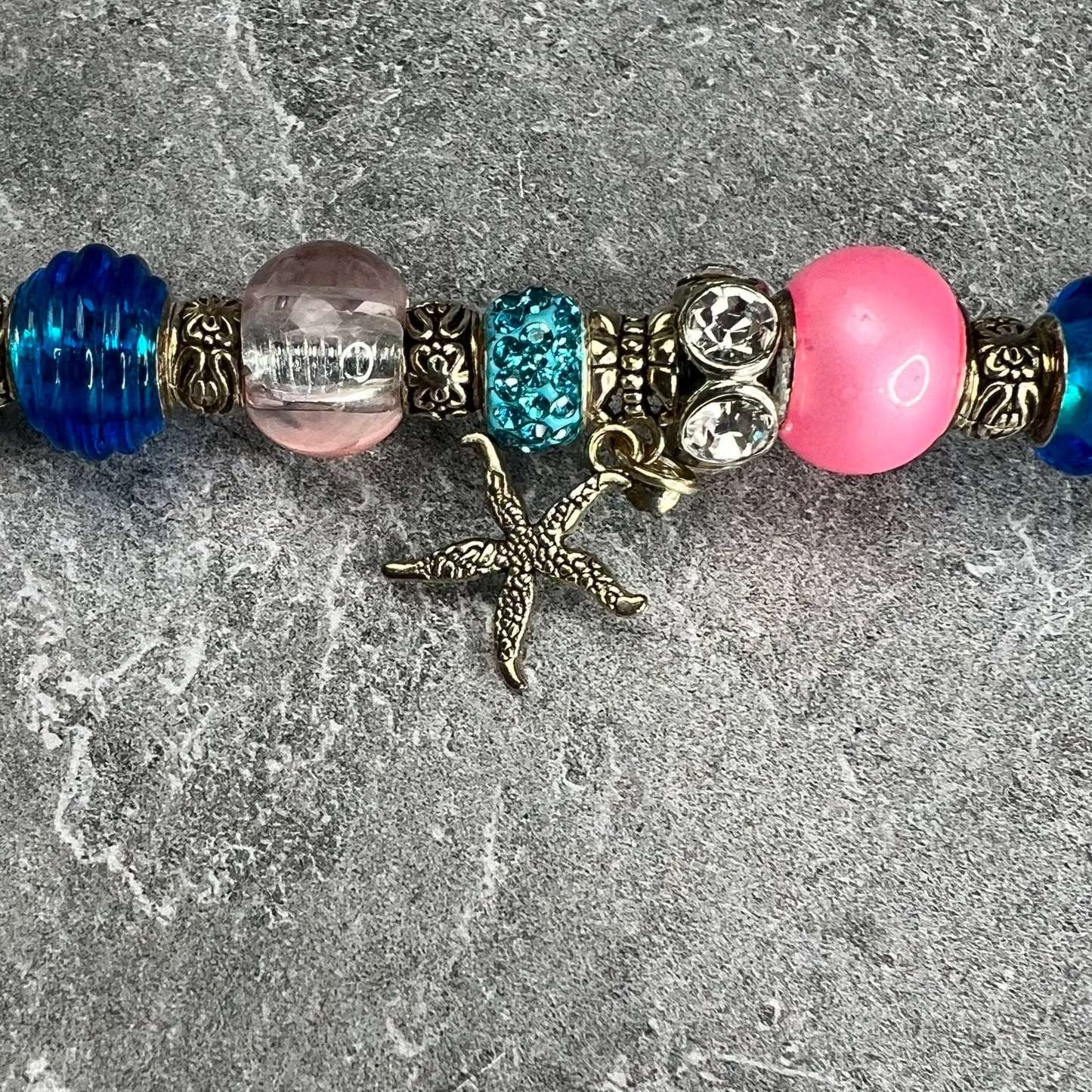 Pink starfish garden stake with a blue metal base — beach-themed outdoor décor.
