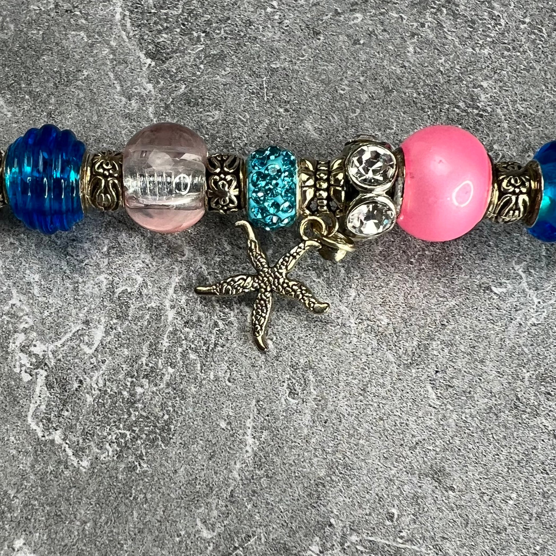 Pink starfish garden stake with a blue metal base — beach-themed outdoor décor.
