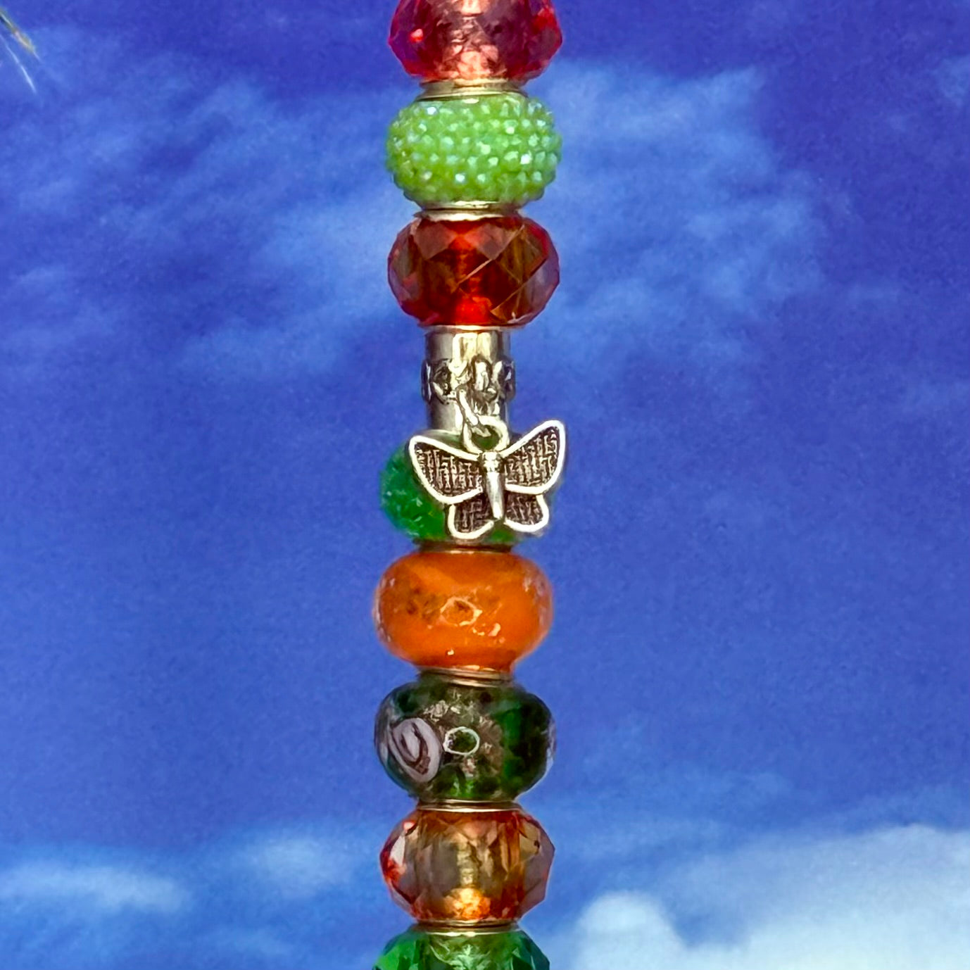 Green and orange metal garden stake with butterfly design — ‘Sunset Meadow’ outdoor decor.
