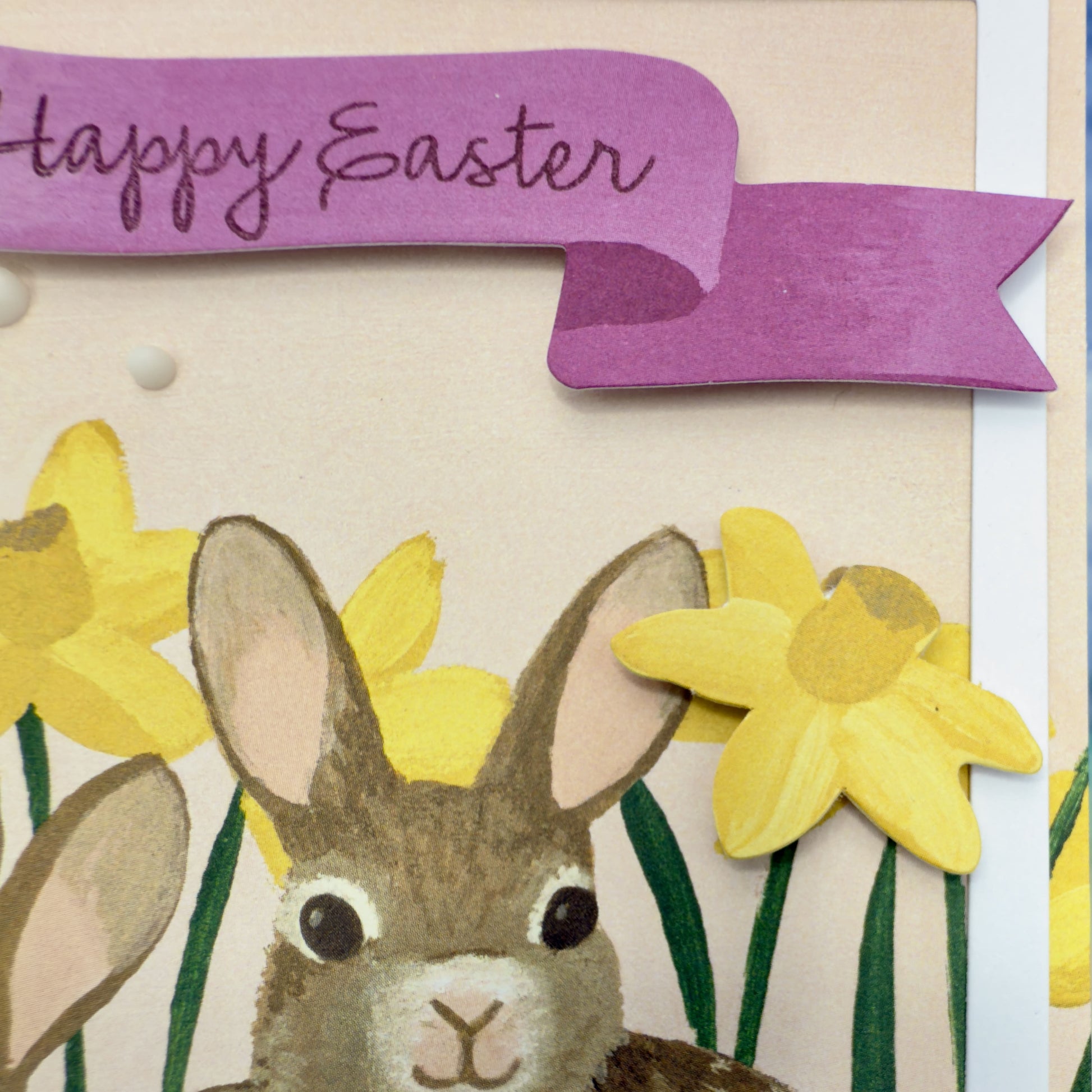 Illustration details of the Happy-Easter greeting card with two fluffy bunnies nestled among floral designs 