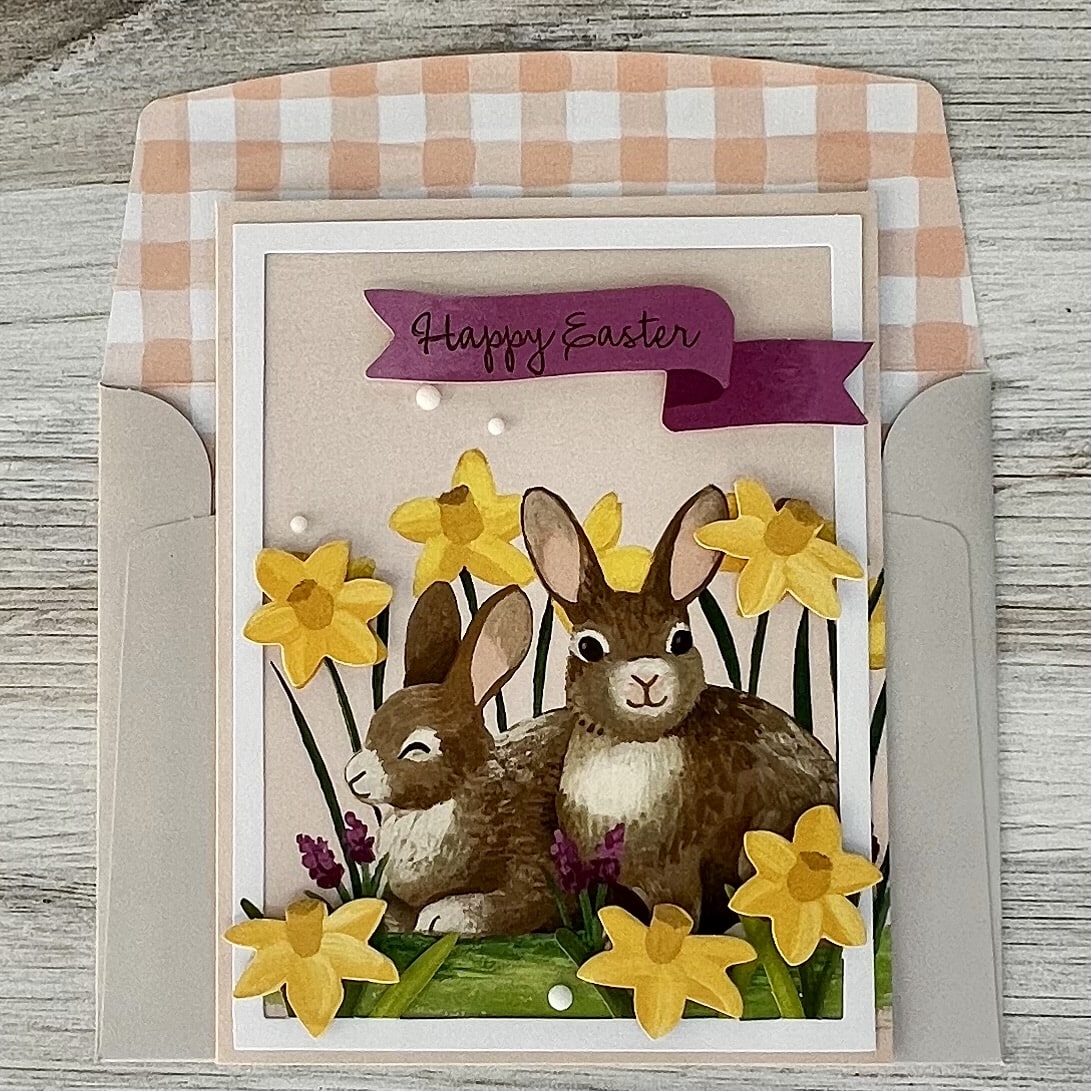 Happy Easter greeting card with two fluffy bunnies nestled in a floral design, from Pineapples and Palm Trees