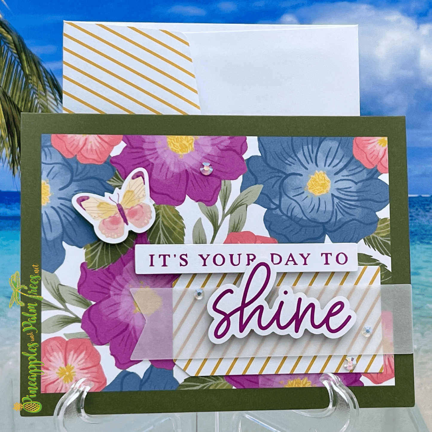 Greeting card with the message ‘It’s Your Day to Shine’ surrounded by cheerful flower illustrations, displayed with its matching envelope.