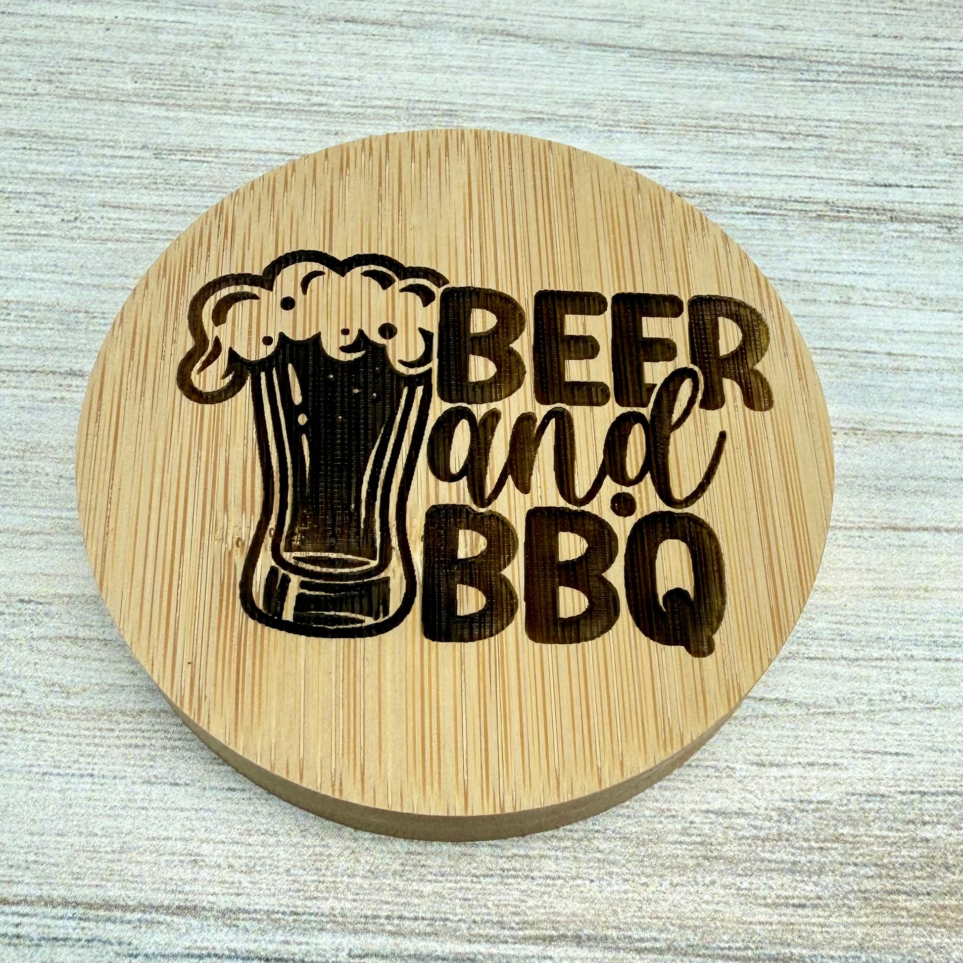 Round laser-engraved bottle opener with “Beer & BBQ” design, perfect for bar or grill use.