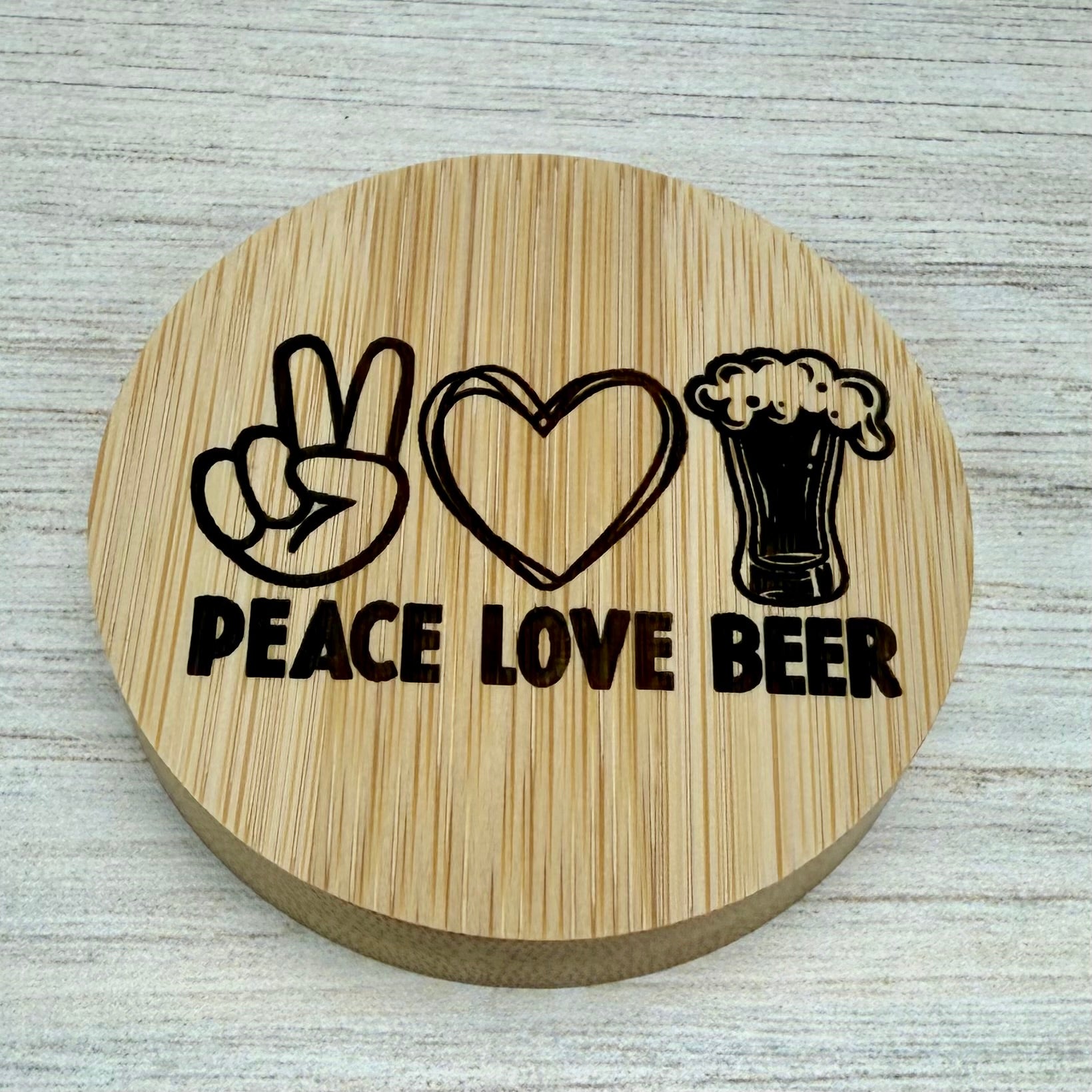 Round laser‑engraved bottle opener with “Peace, Love & Beer” design, ideal for parties or gifts.