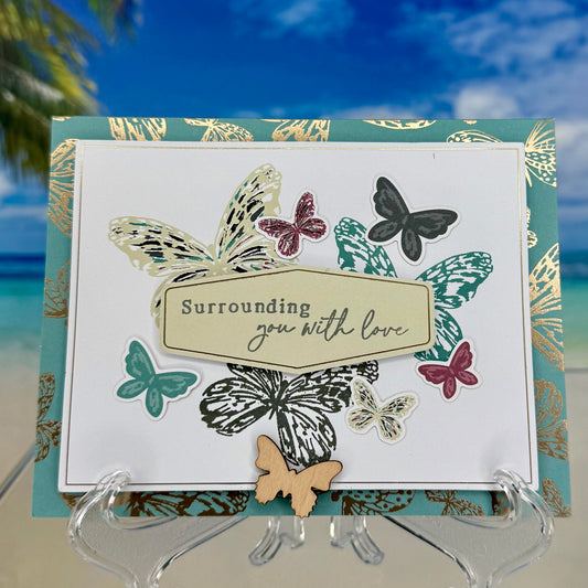 Greeting card “Surrounding You With Love” featuring colorful butterflies illustration on front cover.
