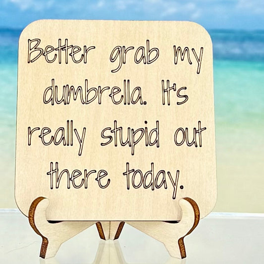 Laser-cut wooden fridge magnet engraved with the quote ‘Better Grab My Dumbrella. It’s Really Stupid Out There Today.’ — handcrafted and humorous décor piece, strong magnet backing, perfect for kitchen or office.