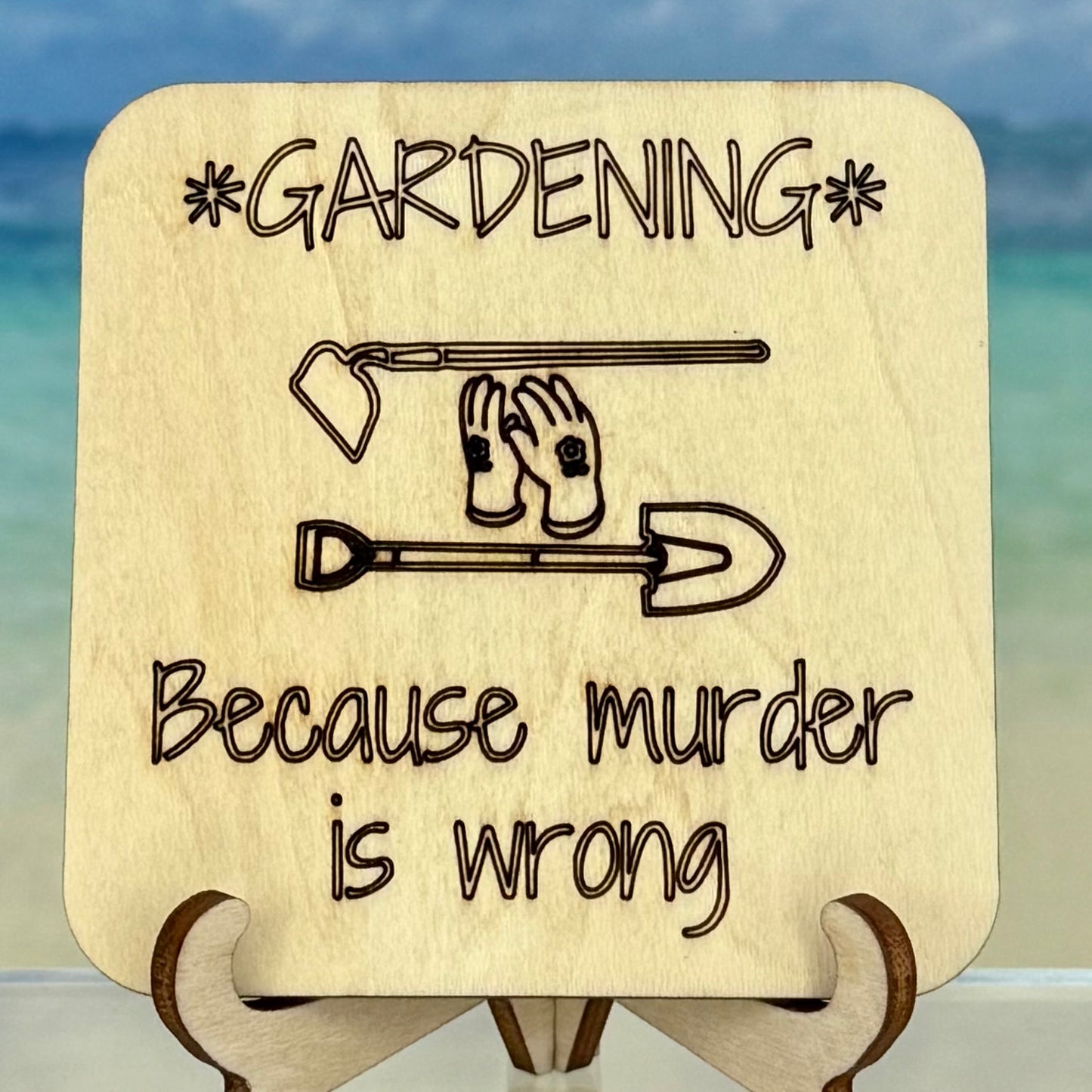 Laser-cut wooden fridge magnet engraved with the quote ‘Gardening because murder is wrong’ along with garden tool icons — handcrafted décor perfect for gardeners with a cheeky sense of humor.