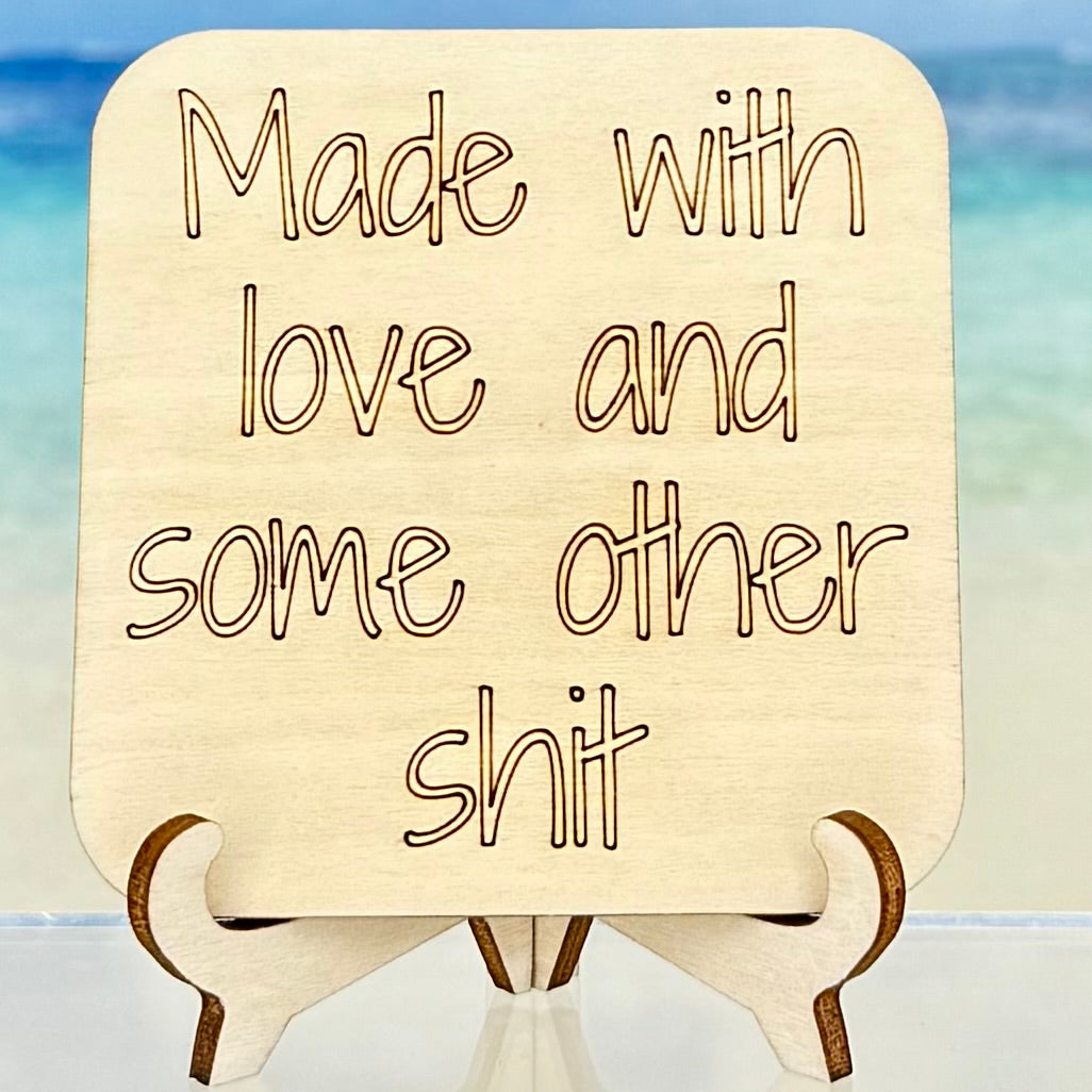 Laser-cut wooden fridge magnet engraved with the quote ‘Made with love and some other shit’ — handcrafted humor décor, perfect for a cheeky gift.