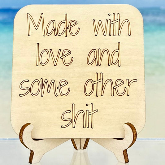 Laser-cut wooden fridge magnet engraved with the quote ‘Made with love and some other shit’ — handcrafted humor décor, perfect for a cheeky gift.