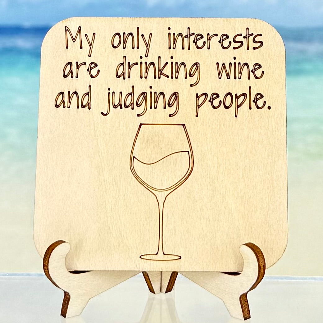 Laser-cut wooden fridge magnet engraved with the quote ‘My only interests are drinking wine and judging people’ alongside a wine glass icon — handcrafted humorous décor gift for wine lovers and witty friends.