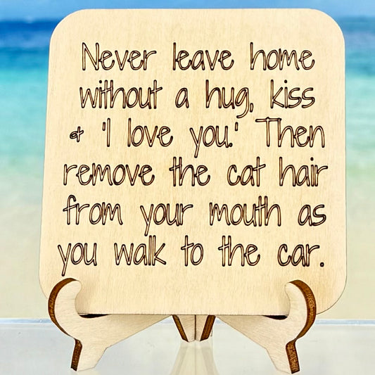 Laser‑cut wooden fridge magnet engraved with the quote ‘Never leave home without a kiss, a hug and “I love you.” Then remove the cat hair from your mouth as you walk to the car.’ — handcrafted décor piece, perfect gift for cat lovers and affectionate homes.